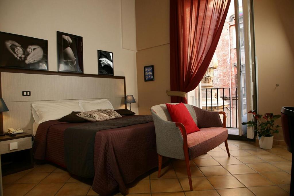 Caravaggio Hotel في نابولي: غرفة نوم بسرير وكرسي ونافذة