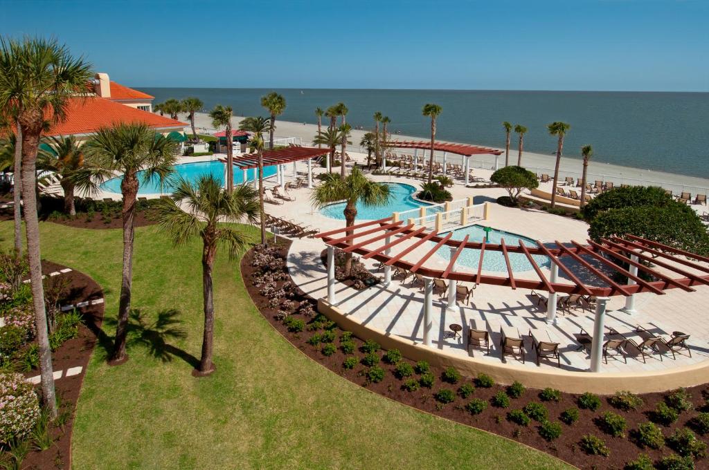a beach area with a pool, chairs, tables and umbrellas at The King and Prince Beach & Golf Resort in Saint Simons Island