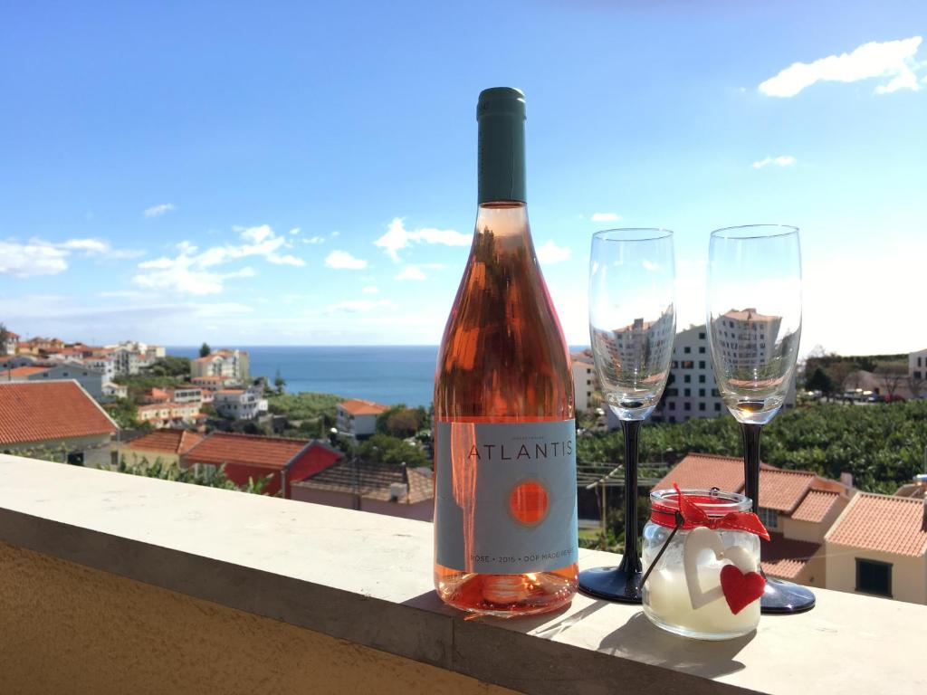 a bottle of wine sitting on a ledge with two glasses at Atlantis Apartment in Câmara de Lobos