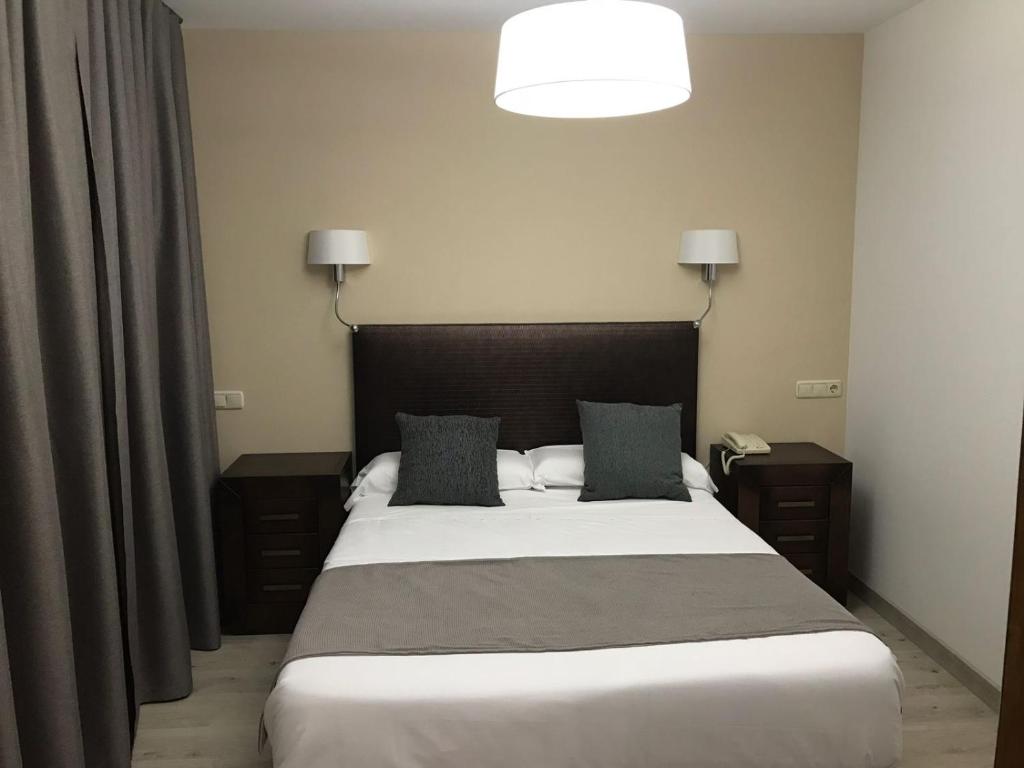 a bedroom with a large bed with two night stands at Hotel Restaurante Santa Cruz in Santa Cruz de Mudela