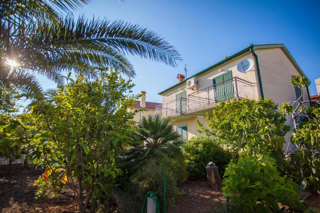 une maison avec un balcon et un palmier dans l'établissement Villa Vosilla Apartments, à Cres