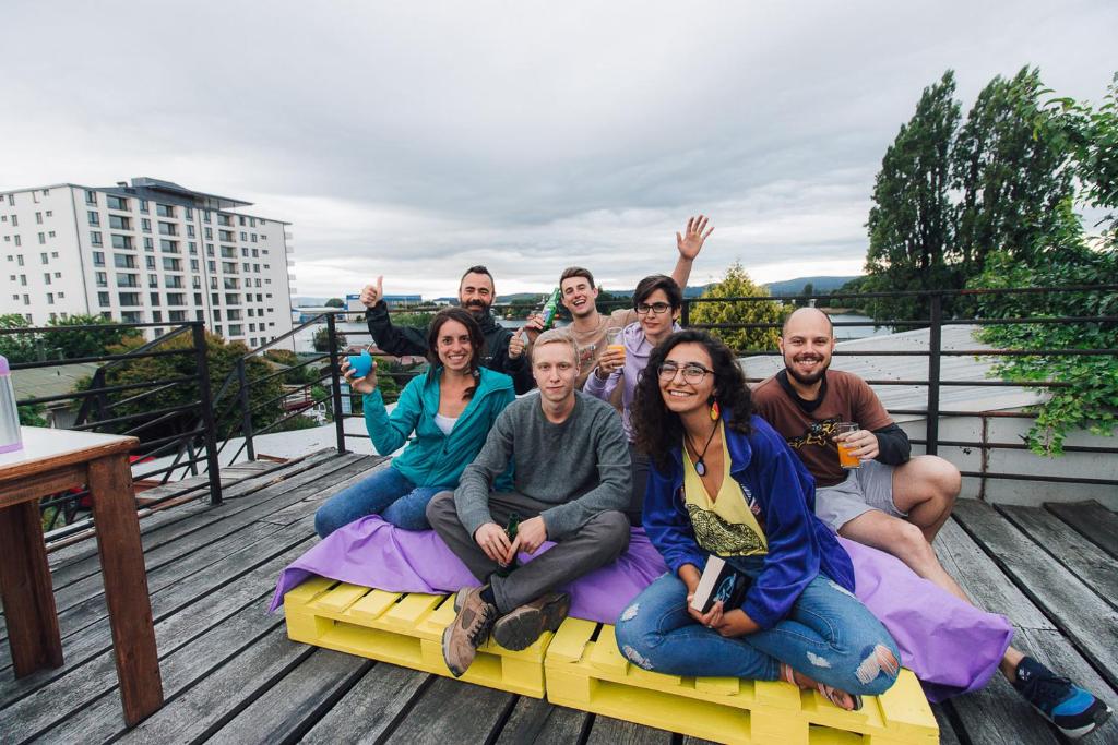 un grupo de personas sentadas en un colchón en una cubierta en Kapai Hostel, en Valdivia