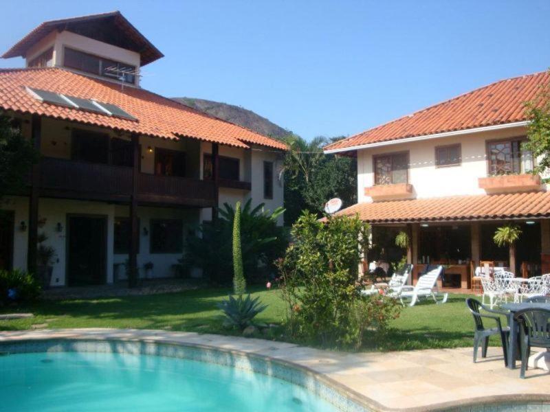 uma casa com piscina em frente a uma casa em Pousada Praia de Itacoatiara em Niterói
