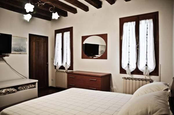 Un dormitorio con una cama y dos ventanas. en Appartamento grazioso e centrale, en Venecia