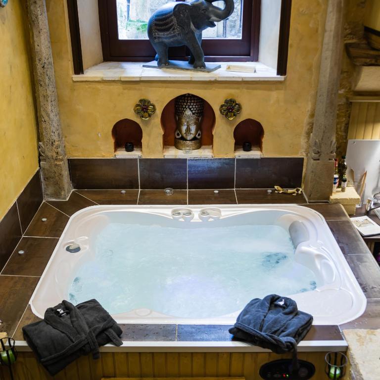 d'un bain à remous avec une statue d'éléphant dans la salle de bains. dans l'établissement Jacuzzi Privé, les 1001 nuits à Sarlat, à Sarlat-la-Canéda