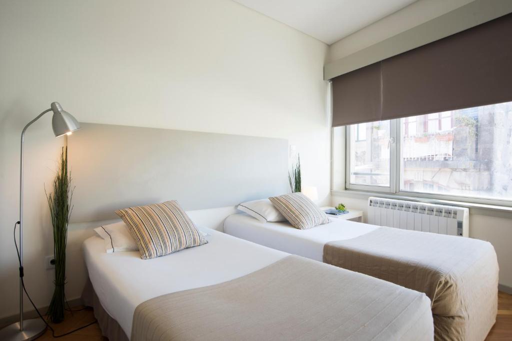 2 camas en una habitación con ventana en bnapartments Trindade, en Oporto