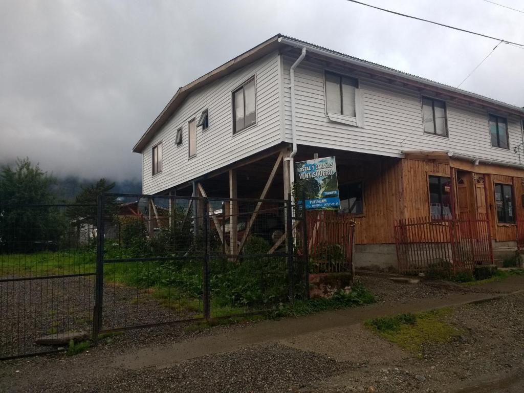 une maison blanche avec une clôture devant elle dans l'établissement Hostal y Cabañas Ventisquero, à Puerto Puyuhuapi
