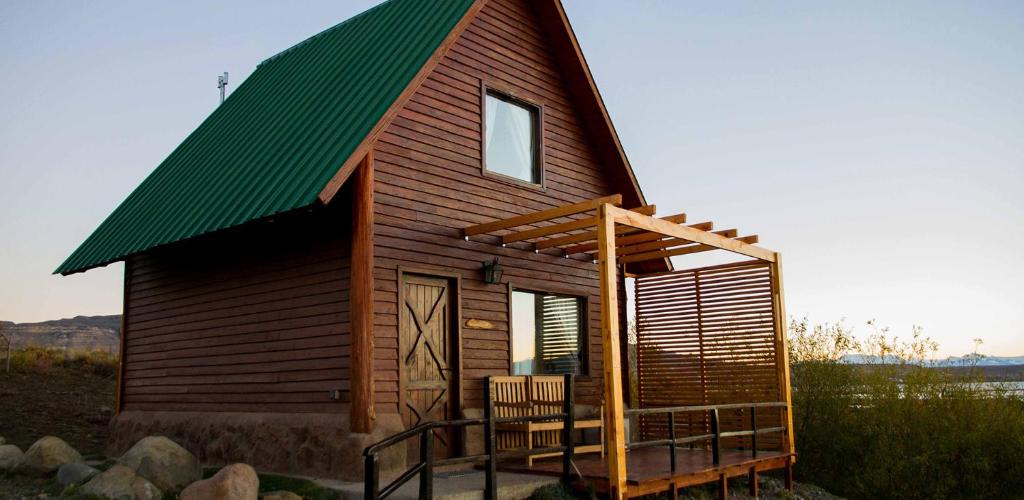 Cabaña pequeña con techo verde y 2 sillas en Brillos Patagónicos en El Calafate