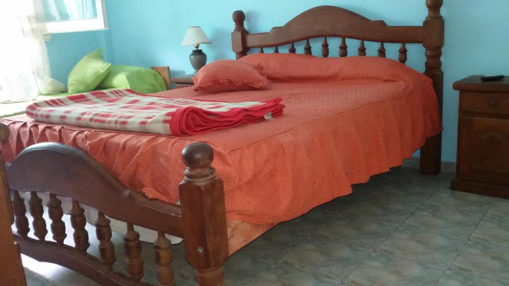 a wooden bed with a red blanket on top of it at Chapadmalal Casas La Bella in Colonia Chapadmalal