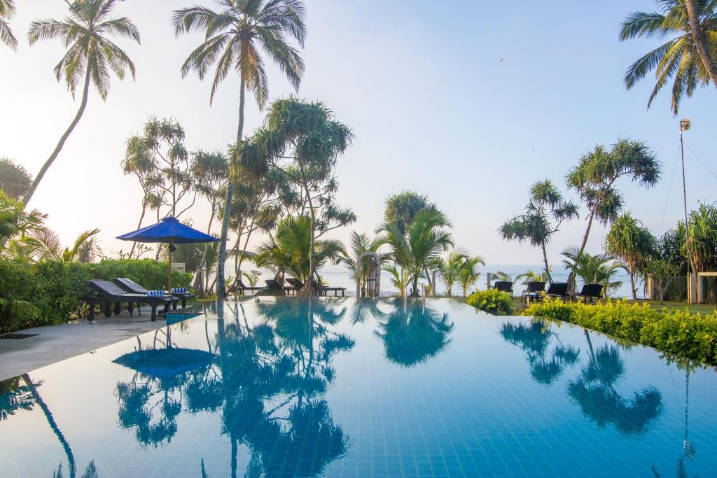 uma piscina num resort com palmeiras em Lanka Beach Bungalows em Tangalle
