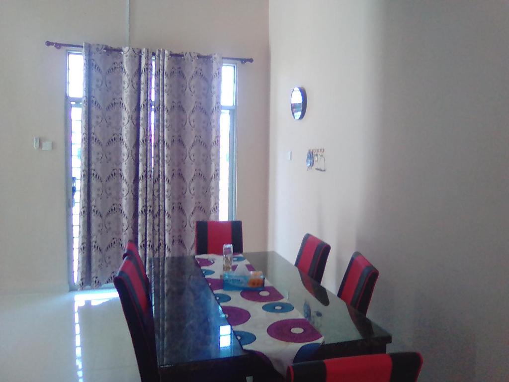 a dining room with a table and red chairs at D'Airport Homestay & Transit Rooms in Kota Bharu
