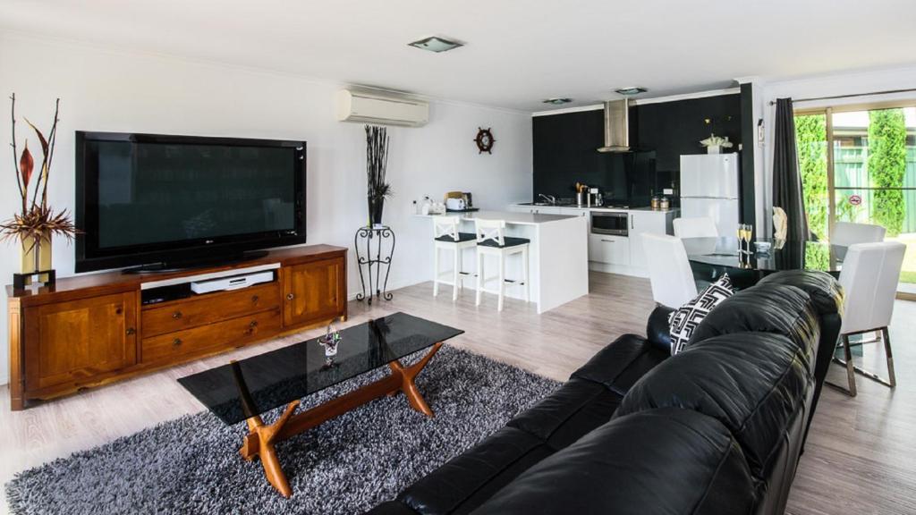 a living room with a black couch and a tv at Lure Bed and Breakfast in Normanville