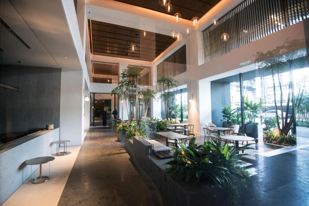 a lobby with tables and chairs and plants at KL Sentral Bangsar Suites (EST) by Luxury Suites Asia in Kuala Lumpur