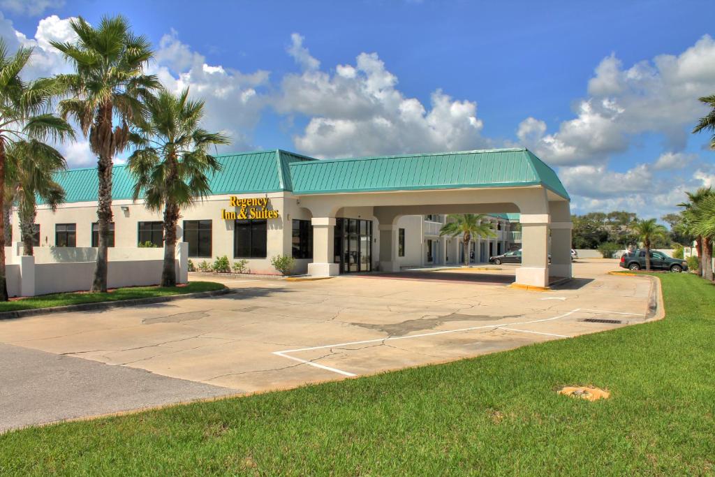 un edificio con techo verde y palmeras en Regency Inn & Suites - Saint Augustine, en St. Augustine Beach