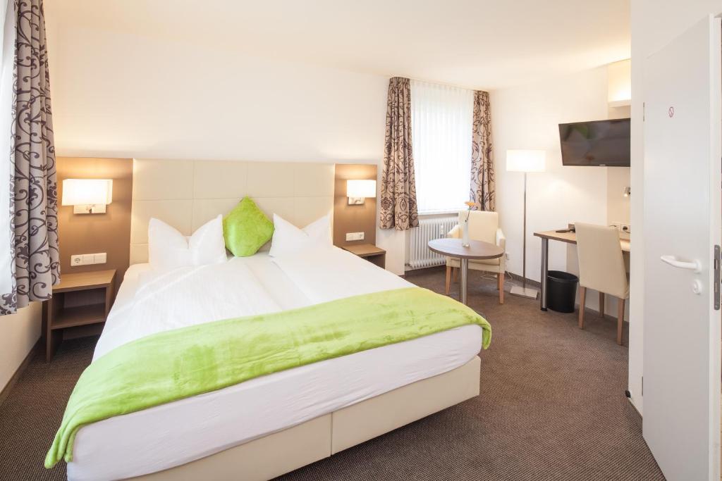 フライブルク・イム・ブライスガウにあるシティ ホテル フライブルクの大きなベッドとデスクが備わるホテルルームです。