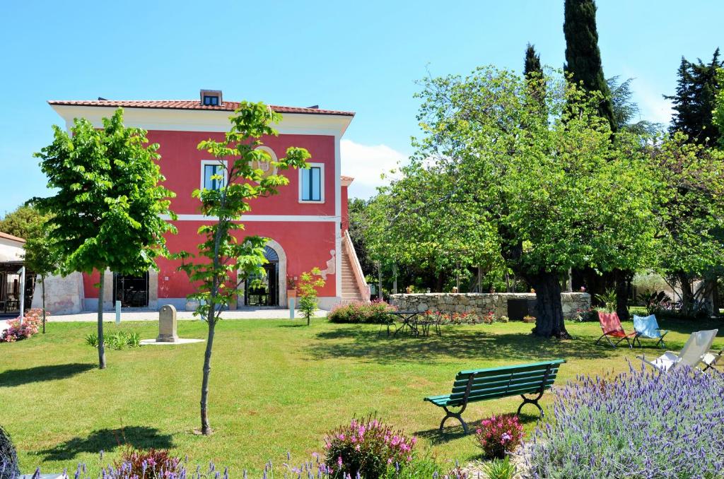 una casa roja con un banco en un jardín en Tenuta Duca Marigliano Boutique Hotel, en Paestum