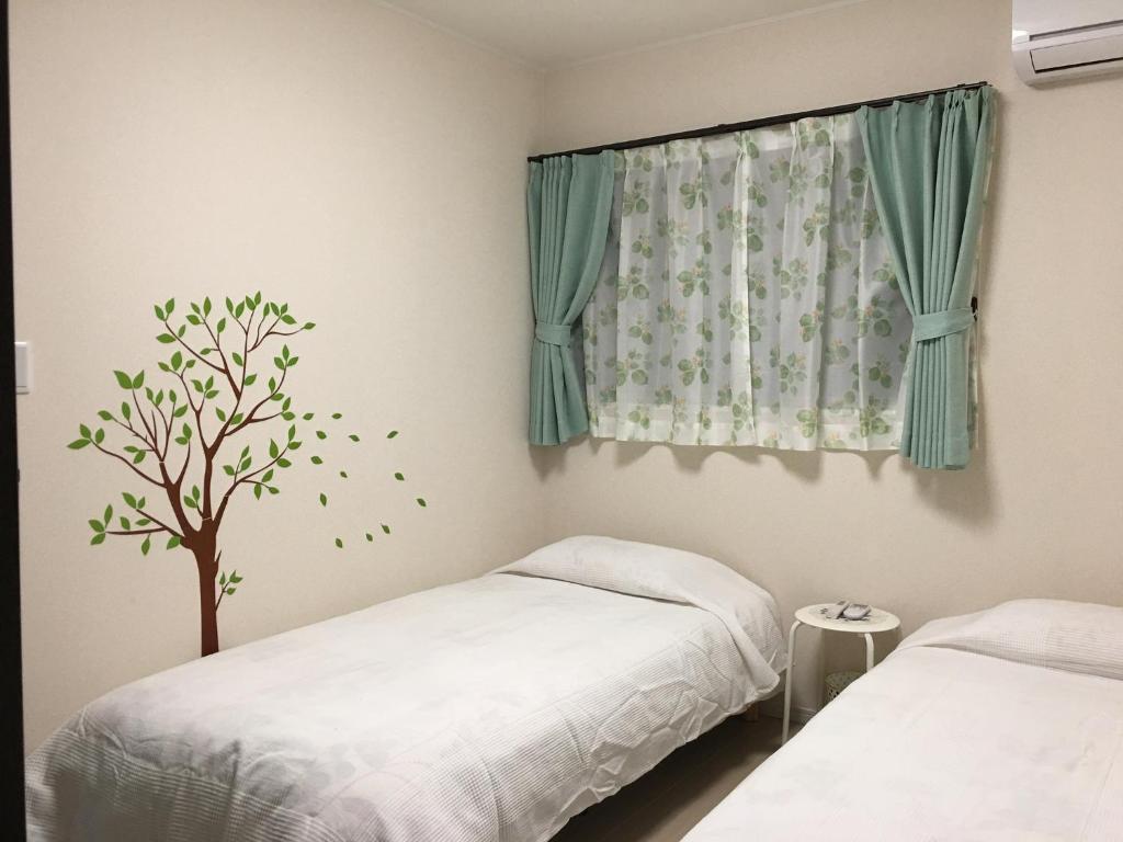 una camera con due letti e un adesivo sull'albero su una finestra di Nara Guesthouse Kaede a Nara