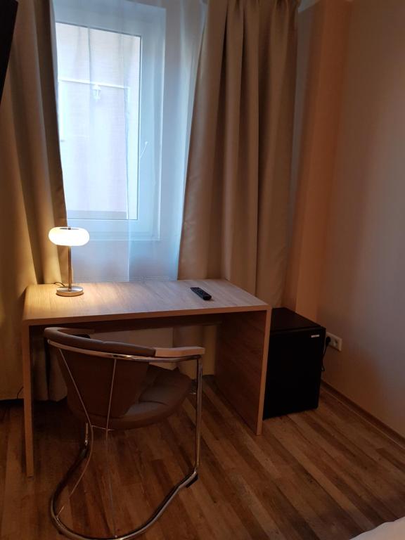a desk with a lamp and a chair next to a window at Hotel-Residenz Oberurseler Hof in Oberursel