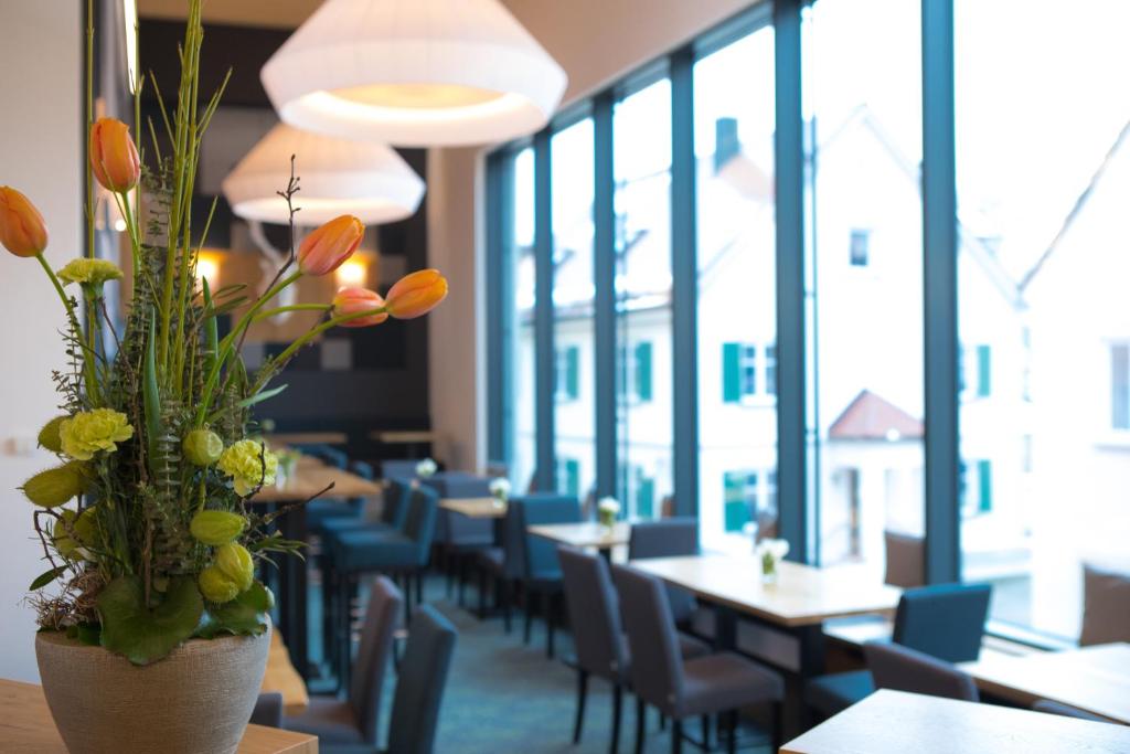 ein Restaurant mit Tischen und Stühlen und eine Vase mit Blumen in der Unterkunft Hotel zum Hirsch in Wertingen