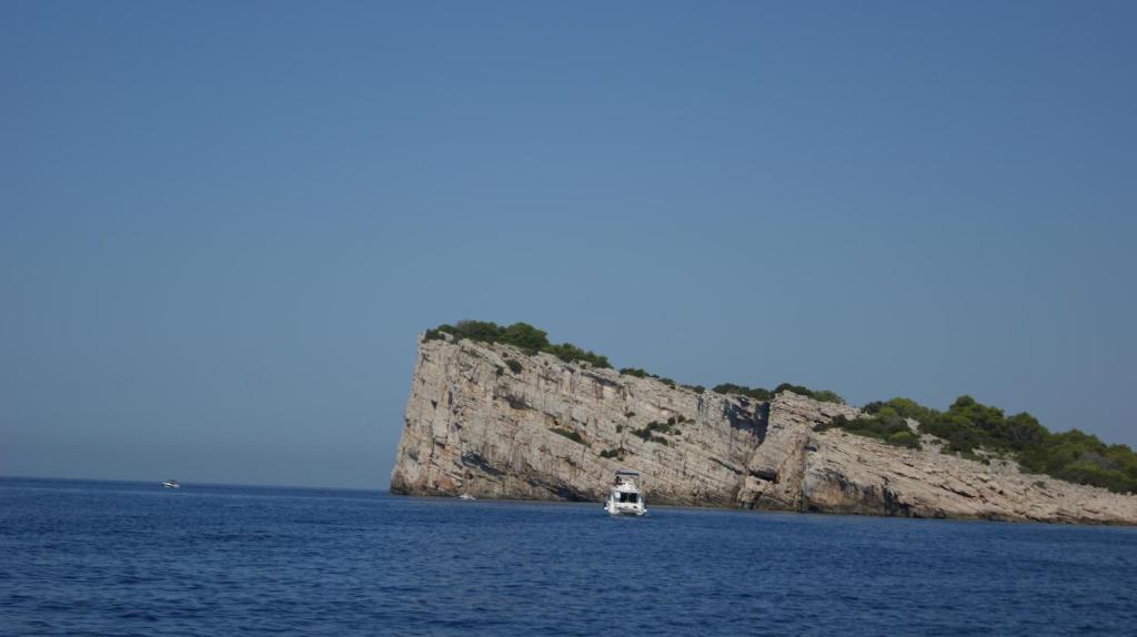 un petit bateau dans l'eau près d'une île rocheuse dans l'établissement J&D, à Dobropoljana