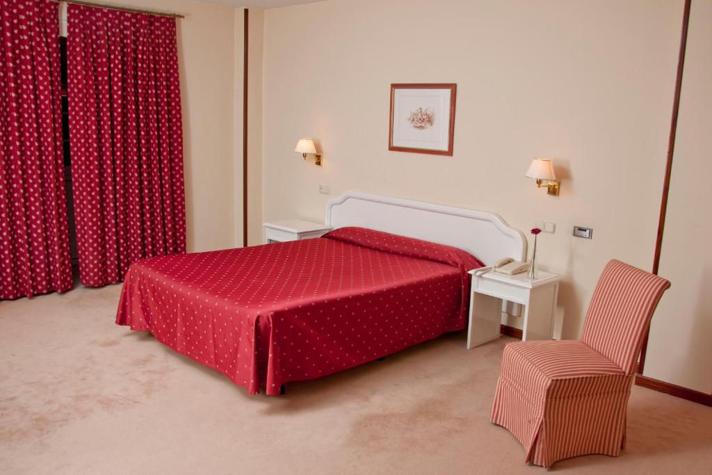 1 dormitorio con 1 cama roja y 1 silla en MLC Benavente, en Benavente