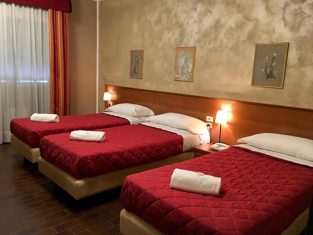 Habitación de hotel con 2 camas con colchas rojas en Hotel Forum, en Rozzano