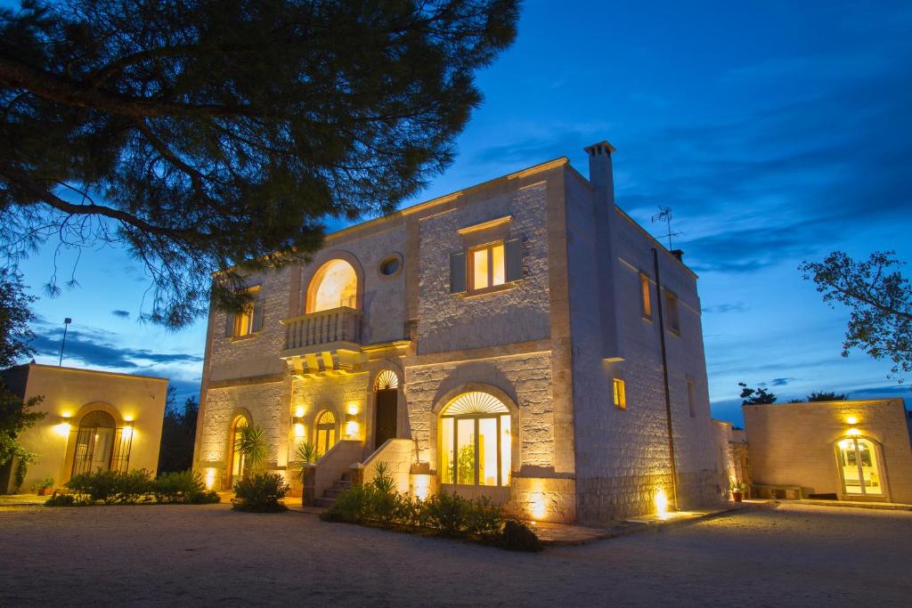 Une grande maison en pierre éclairée la nuit dans l'établissement Masseria Camarda, à Ceglie Messapica