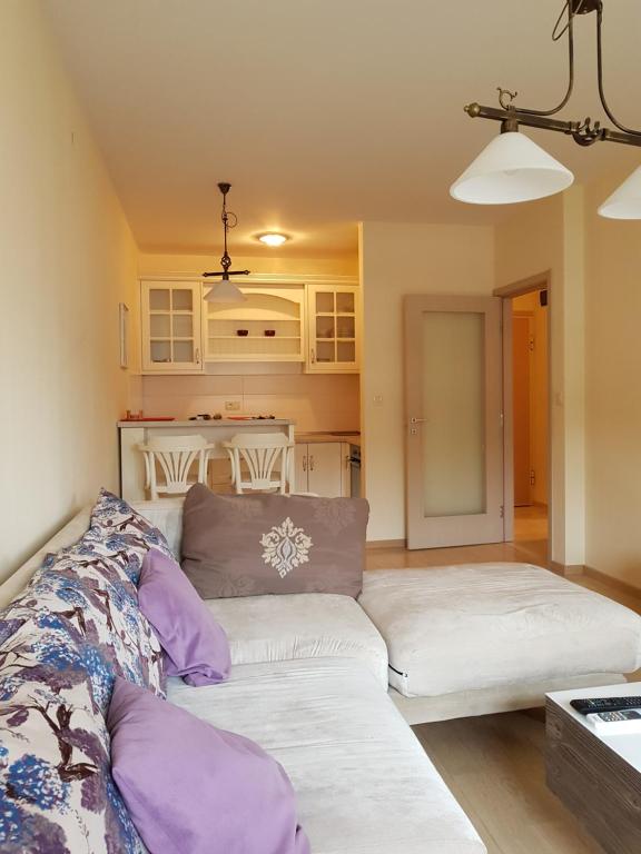 ein Wohnzimmer mit einer weißen Couch und lila Kissen in der Unterkunft Apartment City Life in Podgorica