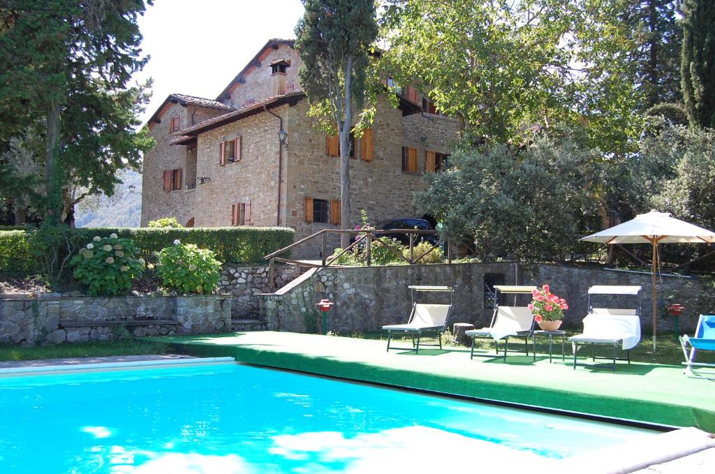 a pool with chairs and umbrellas in front of a house at Agriturismo Borgo Del Senatore in Anghiari
