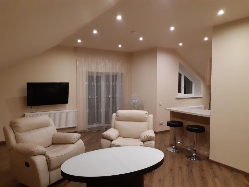 ein Wohnzimmer mit 2 Stühlen, einem Tisch und einem TV in der Unterkunft Zveryno guest house in Vilnius