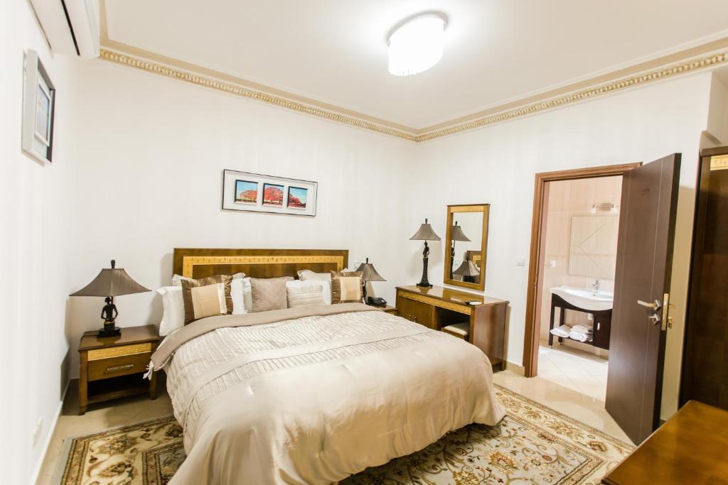 - une chambre blanche avec un lit et un lavabo dans l'établissement Résidence Hôtelière Le Jomonia, à Libreville