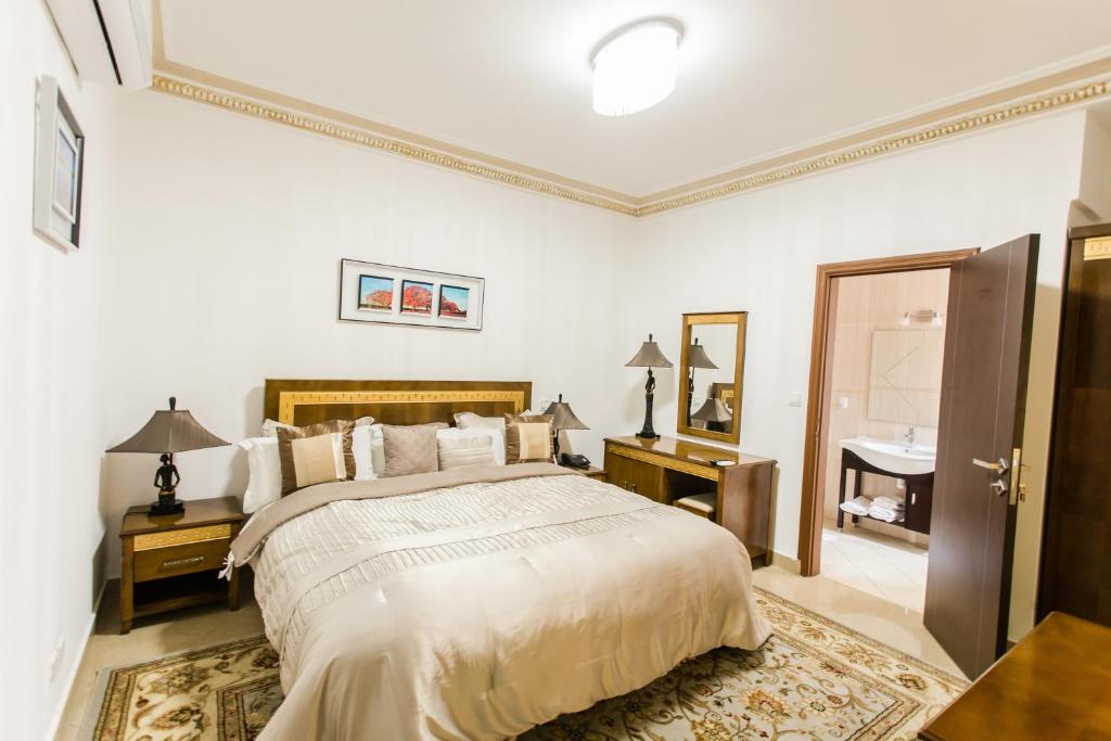 a white bedroom with a bed and a sink at Résidence Hôtelière Le Jomonia in Libreville