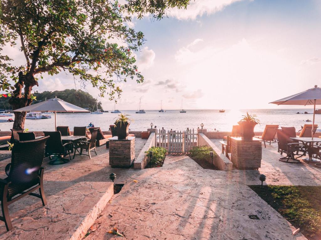 a patio with a view of the water with tables and chairs at Sunset Shores Beach Hotel in Kingstown