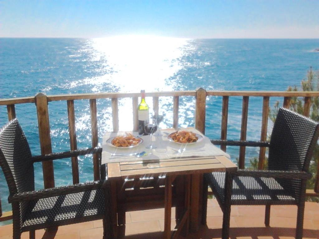 una mesa con dos platos de comida en un balcón con vistas al océano en Sitges Balcony Pool & Seaside Apartment, en Sitges