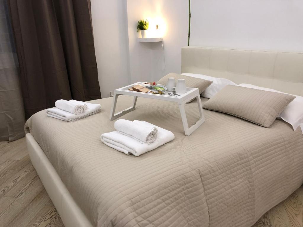 Una cama blanca con toallas y una mesa. en The house of St. Peter, en Roma