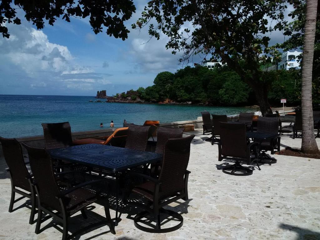 a table and chairs on a beach with the ocean at Sunset Shores Beach Hotel in Kingstown