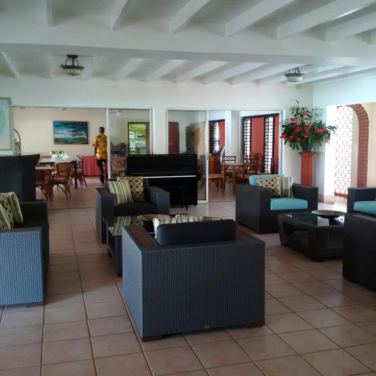 a lobby with couches and tables and a piano at Sunset Shores Beach Hotel in Kingstown