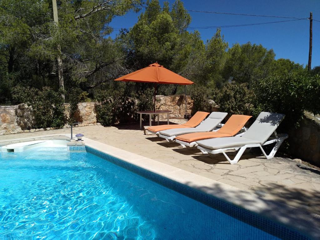 ein Paar Stühle und ein Sonnenschirm neben einem Pool in der Unterkunft Casa Estany in L'Ametlla de Mar