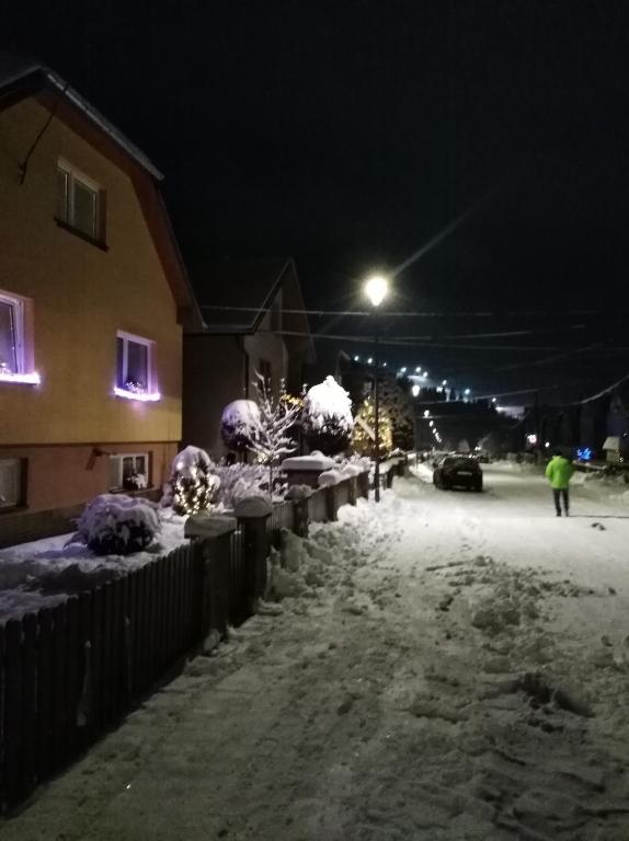 a person walking down a snow covered street at night at Apartmány Grobarčík in Zuberec