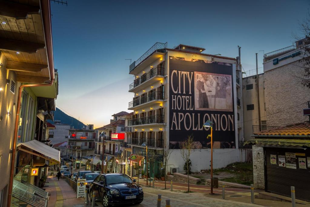 City Hotel Apollonion في كاربنيسي: شارع المدينة فيه سيارات تقف امام مبنى