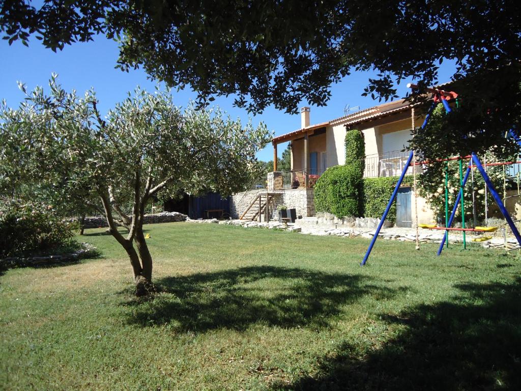 un patio con un árbol y un columpio en le petit coin de Noah en Châteauneuf-Val-Saint-Donat