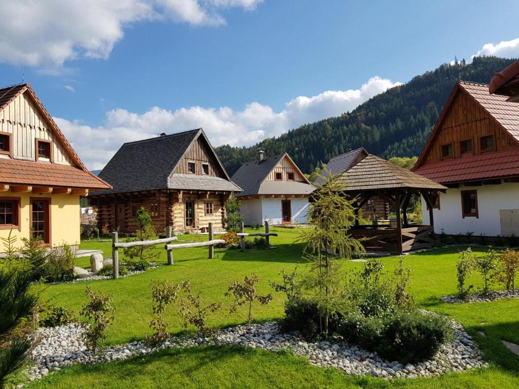 a group of houses in a field with a grass yard at Rezort Gothal Chalupy in Donovaly