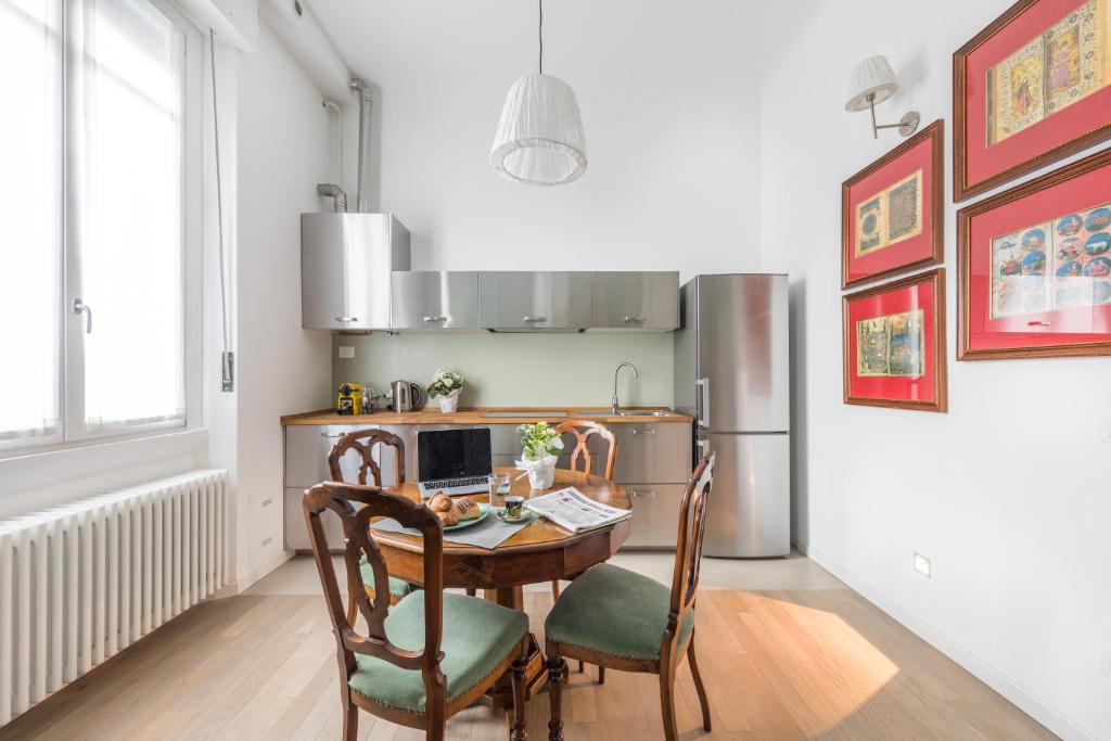 eine Küche mit einem Holztisch und Stühlen sowie eine Küche mit einem Kühlschrank in der Unterkunft grado 14 in Mailand