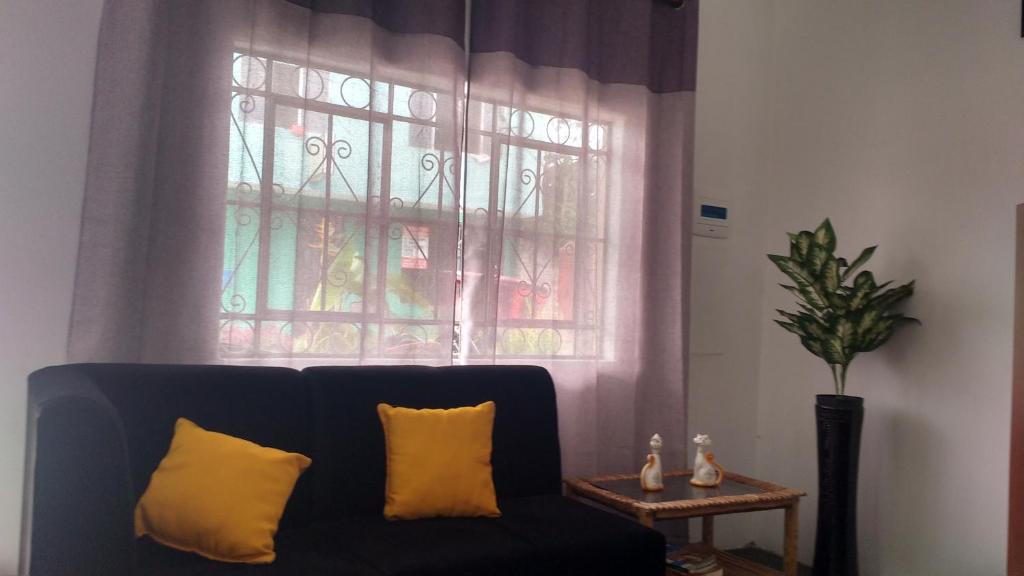 a black couch with two yellow pillows in front of a window at BACHÍG Hospedaje in Moyobamba