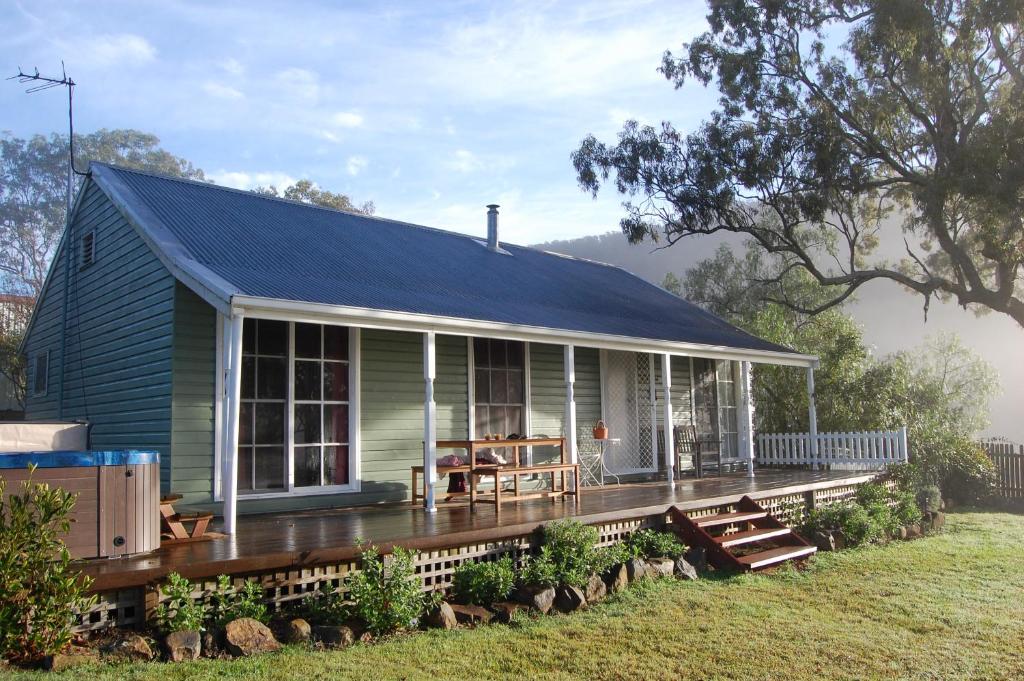 een groen huis met een veranda en een terras bij Cadair Cottages in Rosebrook