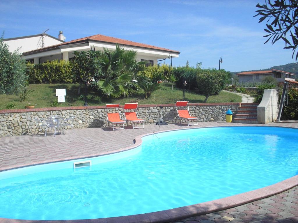 a swimming pool with chairs and a house at Agriturismo Seaview in Capo Vaticano