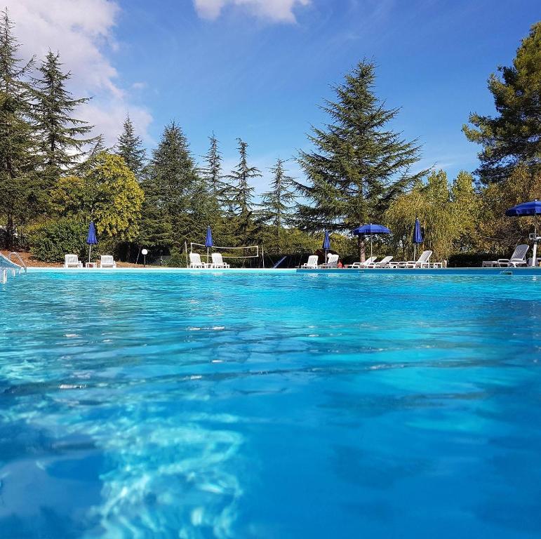 佩斯基奇的住宿－Citrigni，一个带椅子和遮阳伞的蓝色海水游泳池