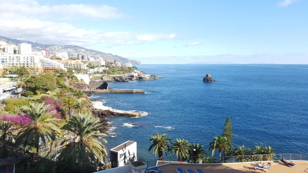 Blick auf das Meer mit Palmen und Gebäuden in der Unterkunft Apartamento Vista Mar e Piscina in Funchal
