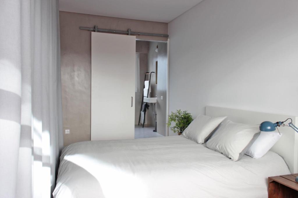 a bedroom with a white bed with a blue lamp at São Miguel 50 in Porto