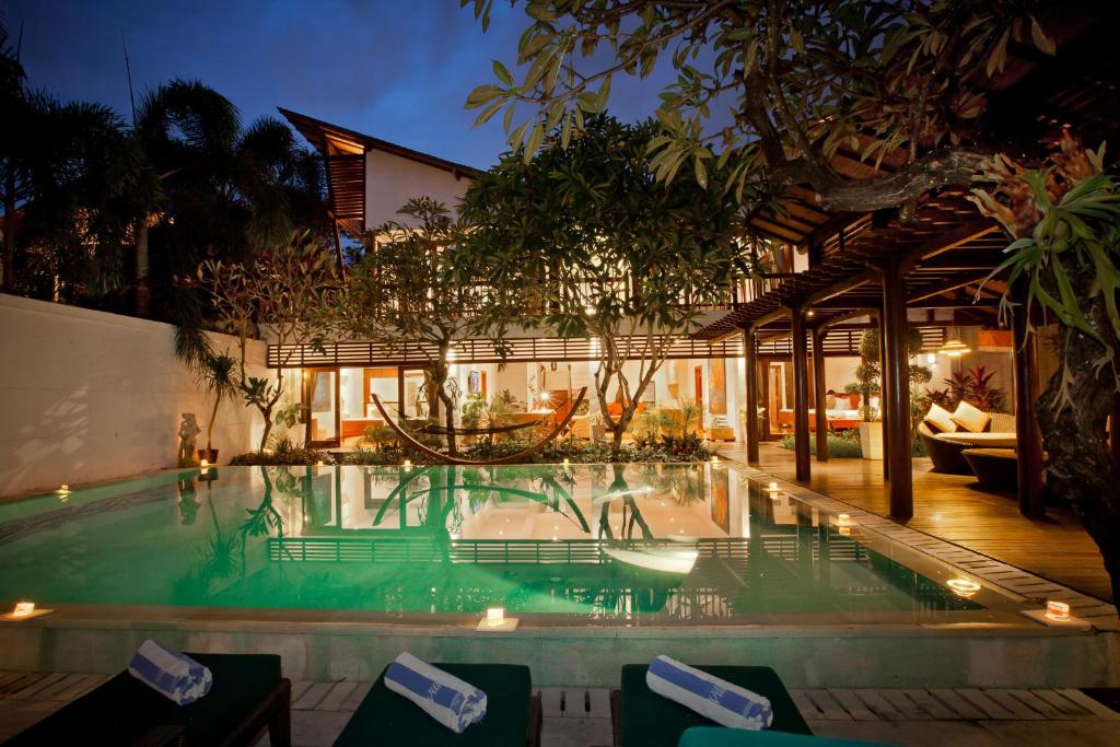 a swimming pool in front of a house at Villa Casis by Nagisa Bali in Sanur